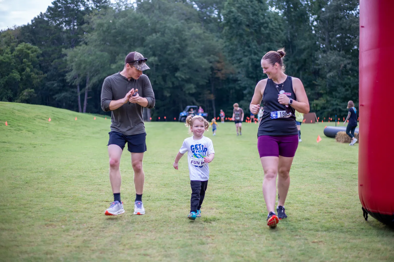 Parents cheering on a young child running the Fun Run