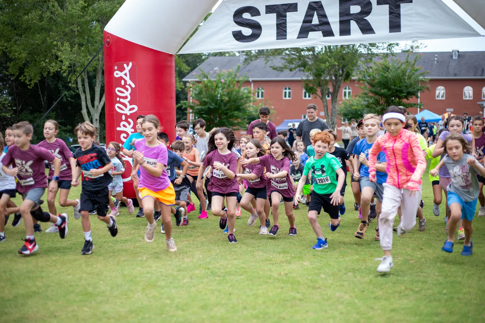 Kids running out of the start arch at the Fun Run