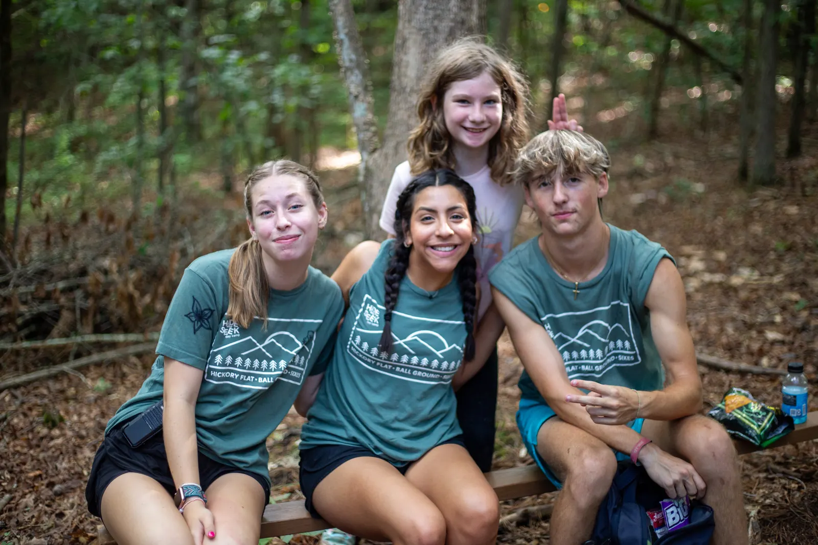 Counselors and a camper sitting together in the woods