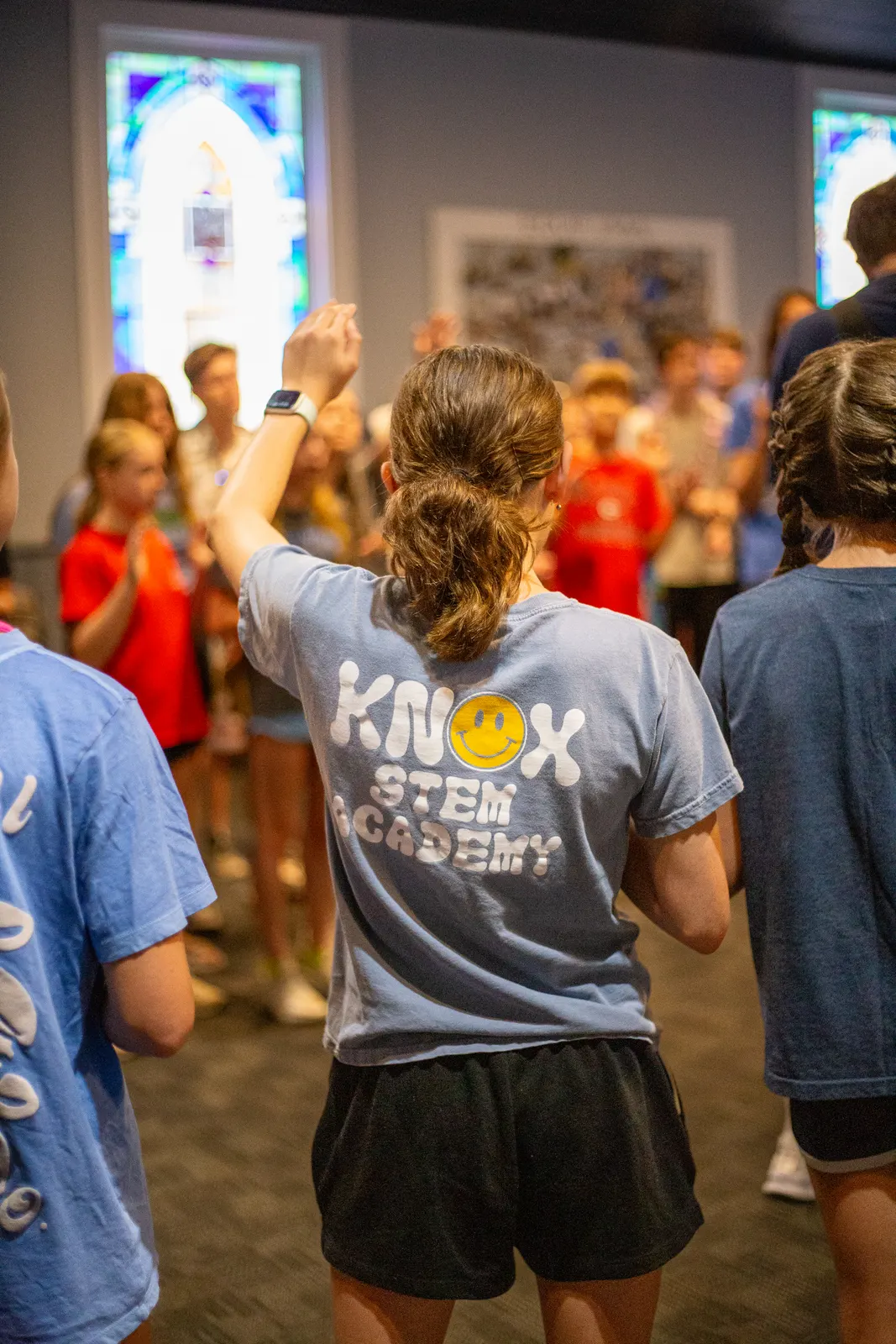 Campers raising their hands indoors