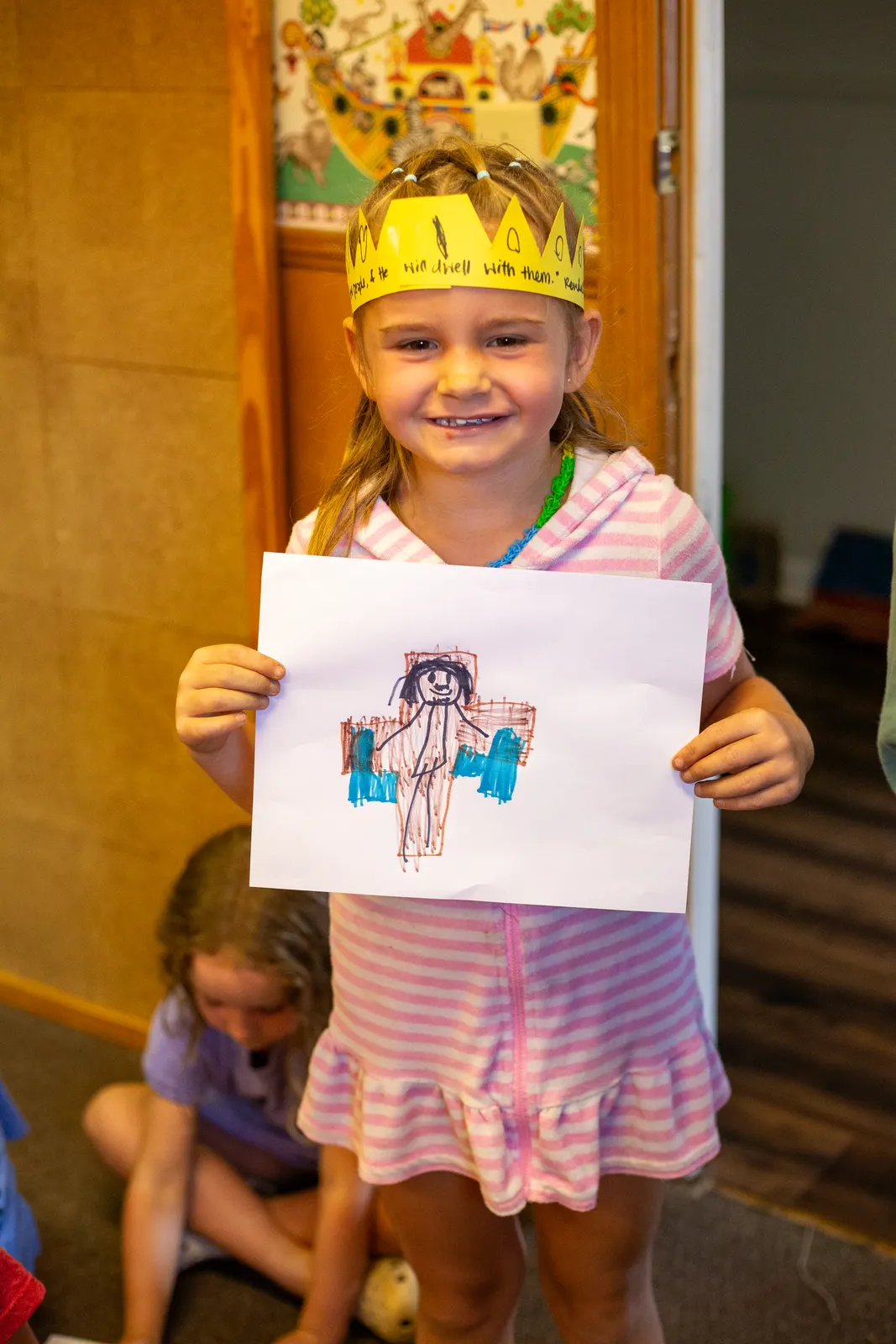Camper in a paper crown holding up a drawing