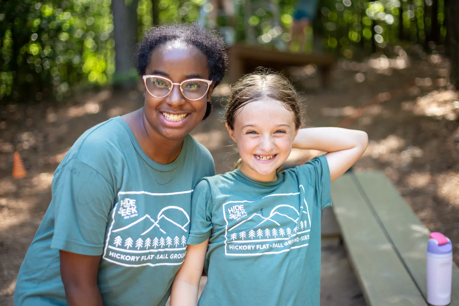 Counselor and camper smiling at a picnic table