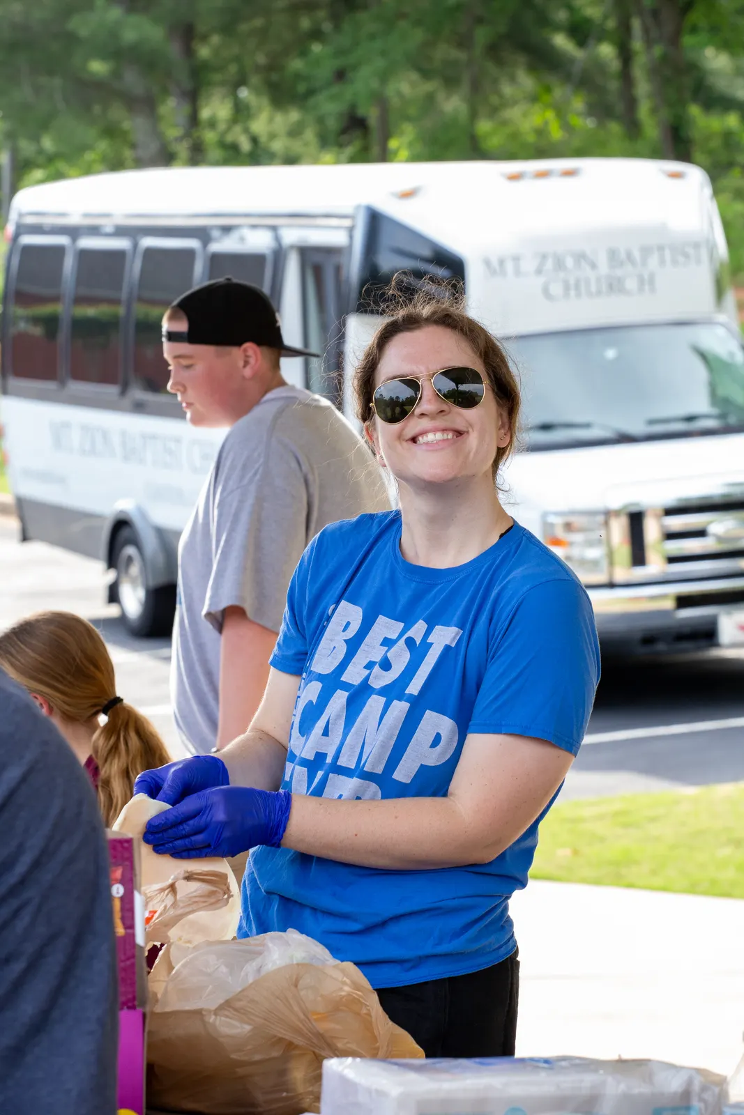 Volunteer in a Best Camp shirt by the van